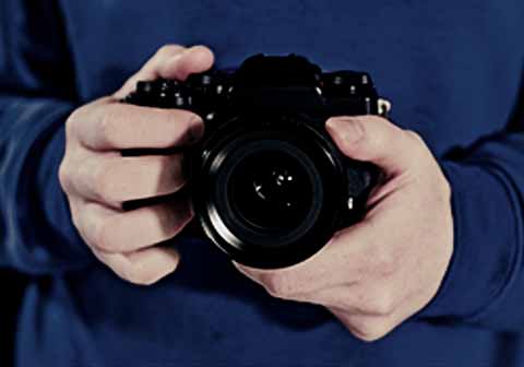 A person holding a DSLR camera in their hands, ready to take a picture